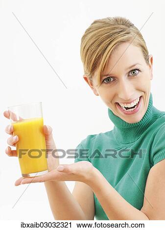 Young woman holding a glass of orange juice View Large Photo Image Stock Image - Young woman holding a glass of orange juice. Fotosearch