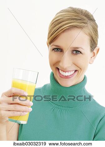 Young woman holding a glass of orange juice View Large Photo Image Stock Photo - Young woman holding a glass of orange juice. Fotosearch