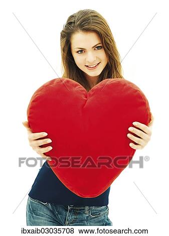 Young woman holding a heart-shaped pillow View Large Photo Image Stock Photo - Young woman holding a heart-shaped pillow. Fotosearch
