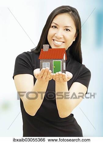 Young woman holding a miniature house View Large Photo Image Stock Photograph - Young woman holding a miniature house. Fotosearch