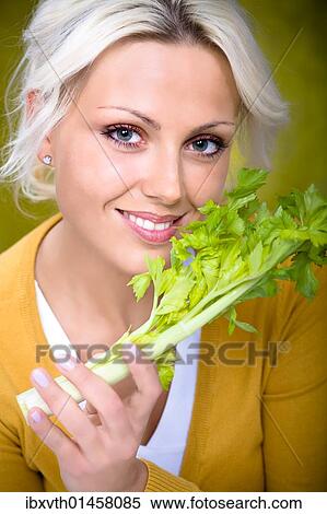 Stock Photography - Young woman holding a stick of celery. Fotosearch