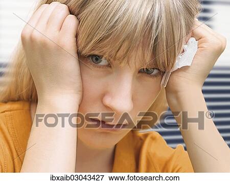 Stock Photo - "Young woman holding a tissue, sick, allergy". Fotosearch