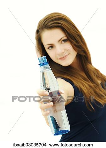Young woman holding a water bottle to the front View Large Photo Image Picture - Young woman holding a water bottle to the front. Fotosearch