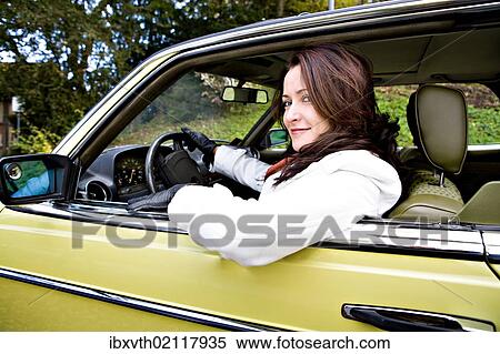 Stock Photography - Young woman in a post-war classic car. Fotosearch