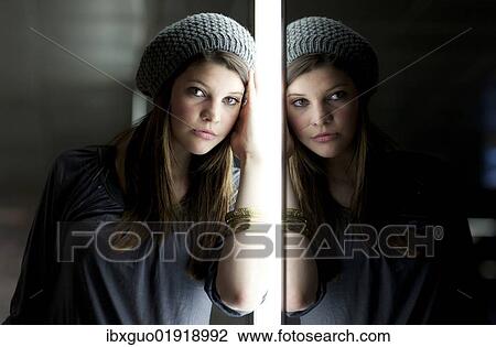 Stock Image - "Young woman in front of a glass wall, portrait with reflection". Fotosearch