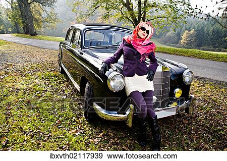Stock Photo - Young woman in front of a post-war classic car. Fotosearch