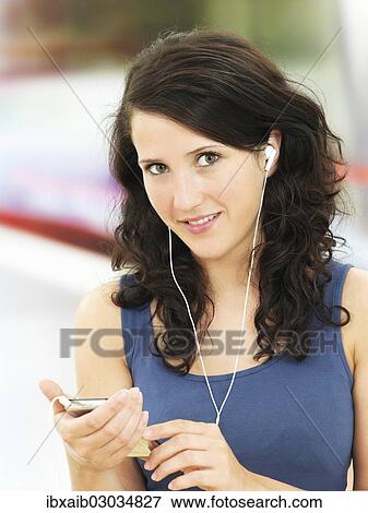 Young woman listening to music at a subway station View Large Photo Image Stock Photo - Young woman listening to music at a subway station. Fotosearch