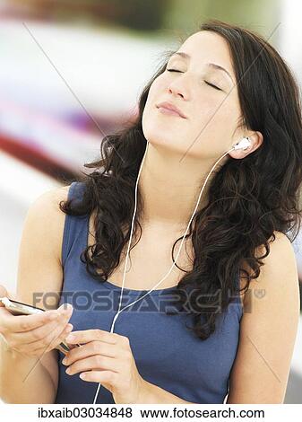 Young woman listening to music at a subway station View Large Photo Image Stock Photo - Young woman listening to music at a subway station. Fotosearch