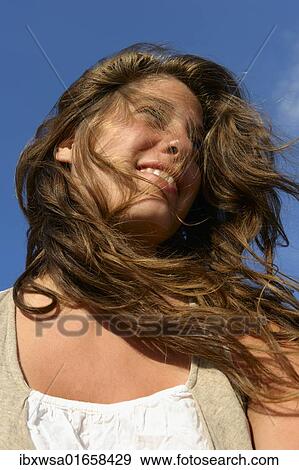 Stock Photo - "Young woman looking upward, her hair tousled by the wind, Finistere departement, Brittany region, France, Europe". Fotosearch