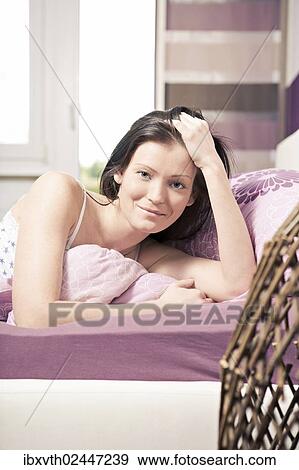 Young woman lying in bed in a bedroom View Large Photo Image Stock Photo - Young woman lying in bed in a bedroom. Fotosearch