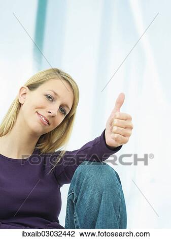 Stock Image - Young woman making a thumbs up gesture. Fotosearch