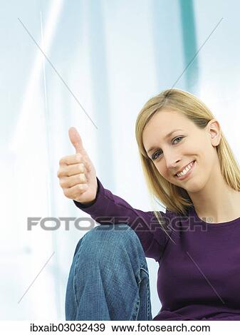 Stock Photo - Young woman making a thumbs up gesture. Fotosearch