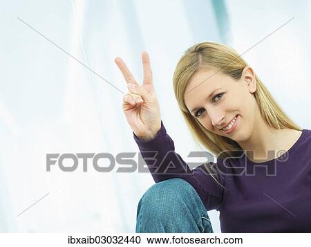 Stock Image - Young woman making a V sign with her hand. Fotosearch