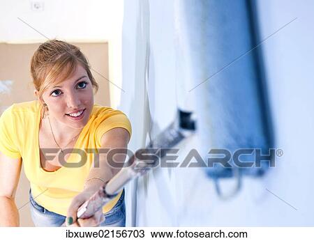 Young woman painting a wall View Large Photo Image Stock Image - Young woman painting a wall. Fotosearch