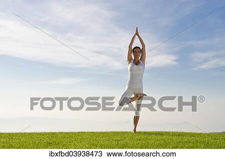 Stock Image - "Young woman practising Hatha yoga, here the pose vrikshasana, tree". Fotosearch
