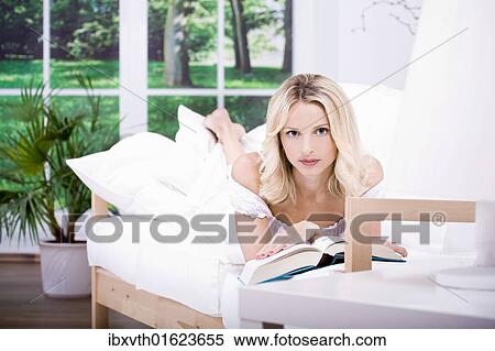 Stock Photography - Young woman reading in living room. Fotosearch