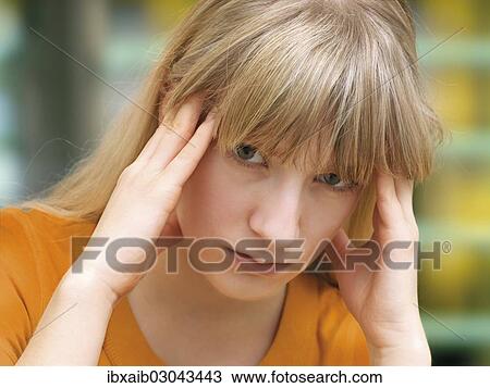 Stock Image - "Young woman rubbing her temples, headache, migraine". Fotosearch