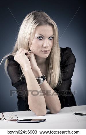 "Young woman sitting at a desk, with moblie phone and glasses, Germany, Europe" View Large Photo Image Stock Image - "Young woman sitting at a desk, with moblie phone and glasses, Germany, Europe". Fotosearch