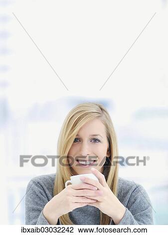 Young woman smiling and holding a cup View Large Photo Image Stock Image - Young woman smiling and holding a cup. Fotosearch