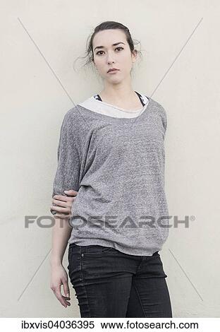 Stock Photography - Young woman standing in front of wall. Fotosearch