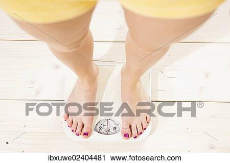 Young woman standing on a scale and checking her weight View Large Photo Image Stock Image - Young woman standing on a scale and checking her weight. Fotosearch