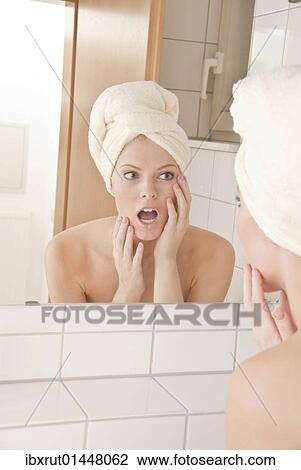 Young woman with a towel wrapped around her head in front of a mirror View Large Photo Image Stock Image - Young woman with a towel wrapped around her head in front of a mirror. Fotosearch