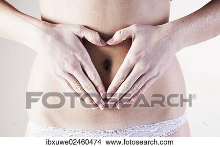 Young woman with her hands forming a heart on her belly View Large Photo Image Picture - Young woman with her hands forming a heart on her belly. Fotosearch