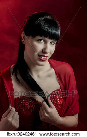 Stock Image - "Young woman with long black hair in a red dress, portrait". Fotosearch