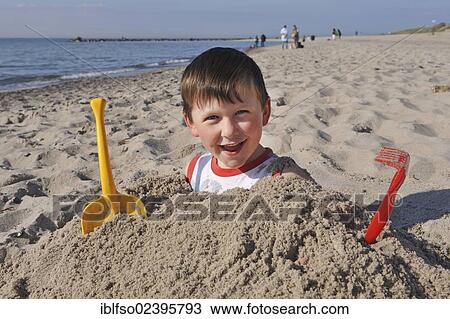 "6-year-old boy, buried in sand up to his shoulders, beach near Ahrenshoop, Baltic Sea, Mecklenburg-Western Pomerania, Germany, Europe" View Large Photo Image Stock Image - "6-year-old boy, buried in sand up to his shoulders, beach near Ahrenshoop, Baltic Sea, Mecklenburg-Western Pomerania, Germany, Europe". Fotosearch