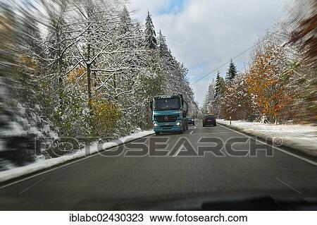 Stock Image - "A country road through a snowy forest near Feldkirchen-Westerham, Bavaria, Germany, Europe". Fotosearch