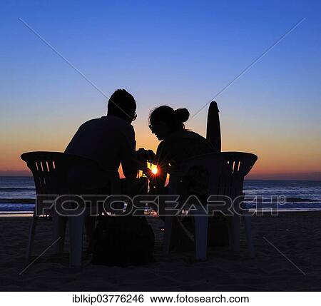 "A couple sitting on the beach at sunset, Sanur Beach, Bali, Indonesia, Asia" View Large Photo Image Stock Photograph - "A couple sitting on the beach at sunset, Sanur Beach, Bali, Indonesia, Asia". Fotosearch