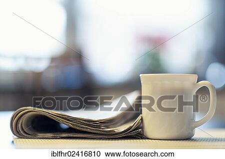 A cup of coffee and a newspaper lying on a kitchen table, Germany, Europe View Large Photo Image Stock Image - A cup of coffee and a newspaper lying on a kitchen table, Germany, Europe. Fotosearch