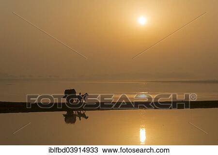 Stock Image - "A donkey cart crossing the Yamuna river on a dam at sunrise, Vrindavan, Uttar Pradesh, India, Asia". Fotosearch