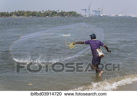 Stock Image - "A fisherman throwing his net, Port of Kochi, Kochi, Kerala, India, Asia". Fotosearch