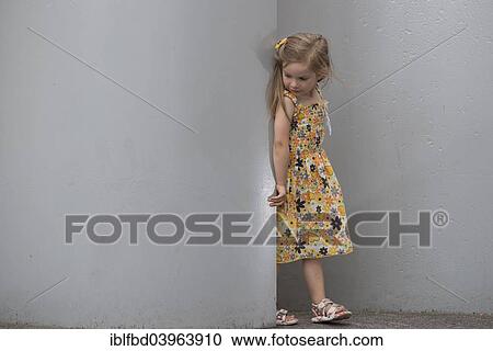 Stock Image - "A girl, 3 years, wearing a dress, standing between walls, Germany, Europe". Fotosearch