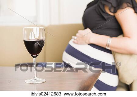 Stock Image - A glass of red wine and a pregnant woman. Fotosearch