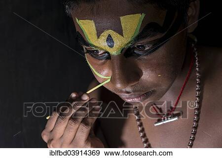 Stock Photo - "A Katakali artist is applying the make-up of the character Arjun for the Santhana Gopalam play during a temple festival, Ayroor, Kerala, India, Asia". Fotosearch
