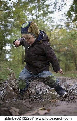 "A little boy is jumping with joy into a muddy puddle during an autumn walk, Brandenburg, Germany, Europe" View Large Photo Image Stock Photo - "A little boy is jumping with joy into a muddy puddle during an autumn walk, Brandenburg, Germany, Europe". Fotosearch