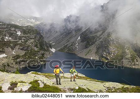 "A man and a woman hiking at the Lago della Crosa mountain lake, Bavona Valley, Val Calneggia, Valle Maggia, Ticino, Switzerland, Europe" View Large Photo Image Stock Image - "A man and a woman hiking at the Lago della Crosa mountain lake, Bavona Valley, Val Calneggia, Valle Maggia, Ticino, Switzerland, Europe". Fotosearch