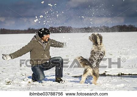 Stock Photograph - "A man and his dog are playing in the snow on a field near Wustermark, Havelland, Brandenburg, Germany, Europe". Fotosearch