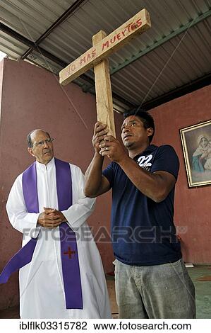 "A man is holding up a cross with the inscription """"No Mas Muertos"""", Spanish for """"No more dead"""", mass being held at a shelter for Latin American migrants passing through Mexico on their way to the U. S, Ixtepec, Oaxaca, Mexico, North America" View Large Photo Image Stock Image - "A man is holding up a cross with the inscription """"No Mas Muertos"""", Spanish for """"No more dead"""", mass being held at a shelter for Latin American migrants passing through Mexico on their way to the U. S, Ixtepec, Oaxaca, Mexico, North America". Fotosearch
