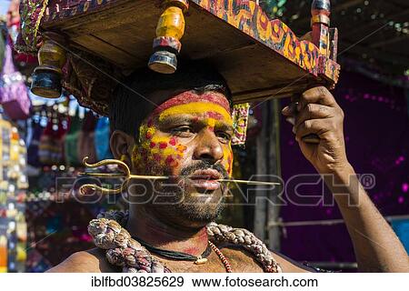 Stock Photo - "A man with a small brass trident pierced through his cheek is collecting money for religious purposes at the weekly flea market, Anjuna, Goa, India, Asia". Fotosearch