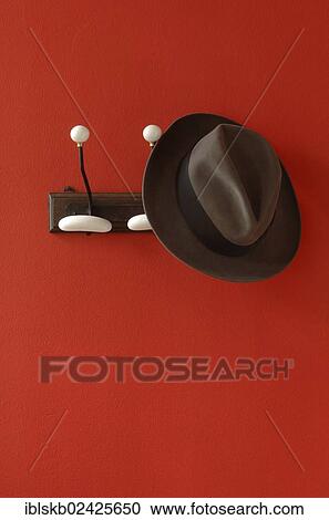 A man's hat is hanging on nostalgic clothes hooks on a red wall View Large Photo Image Stock Image - A man's hat is hanging on nostalgic clothes hooks on a red wall. Fotosearch