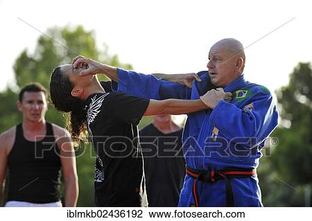 "A martial arts instructor is showing a defensive move on a student in a park, two men watching" View Large Photo Image Stock Image - "A martial arts instructor is showing a defensive move on a student in a park, two men watching". Fotosearch