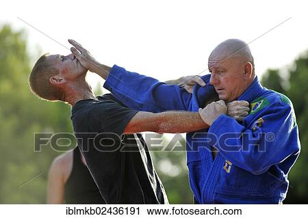 A martial arts instructor is demonstrating a defensive move on a student in a park View Large Photo Image Stock Image - A martial arts instructor is demonstrating a defensive move on a student in a park. Fotosearch