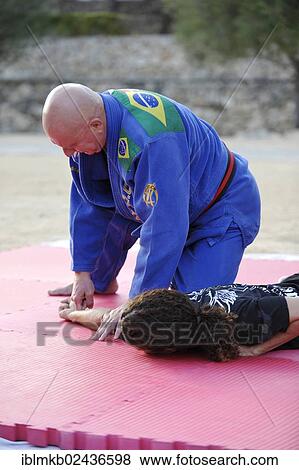 A martial arts instructor is teaching a grip to a student on a mat in a park View Large Photo Image Stock Photo - A martial arts instructor is teaching a grip to a student on a mat in a park. Fotosearch