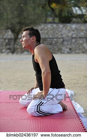 A martial arts student is kneeling on an exercise mat in a park View Large Photo Image Stock Photo - A martial arts student is kneeling on an exercise mat in a park. Fotosearch
