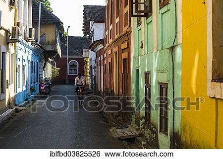Stock Photograph - "A small lane with colourful houses and a cyclist, Panaji, Goa, India, Asia". Fotosearch