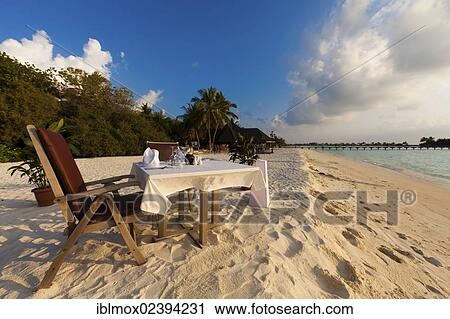 Stock Image - "A table laid for dinner standing on the beach, Paradise Island at the back, Lankanfinolhu, North Male Atoll, Republic of Maldives, Indian Ocean, Asia". Fotosearch
