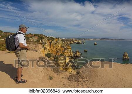 Stock Photography - "A tourist, 56 years, enjoying the views, Praia do Camilo beach, Praia Dona Ana beach at back, Lagos, Algarve, Portugal, Europe". Fotosearch